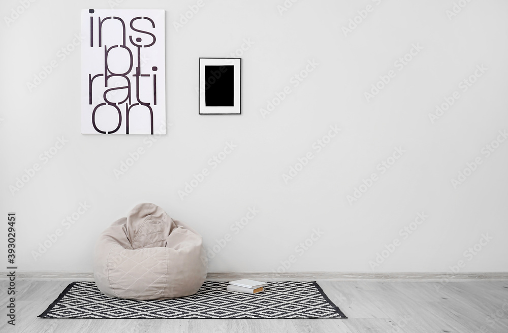 Stylish bean bag chair with books near light wall in room