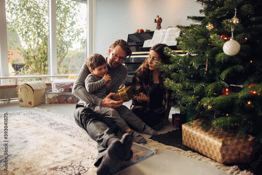 Parents giving Christmas gifts to their son