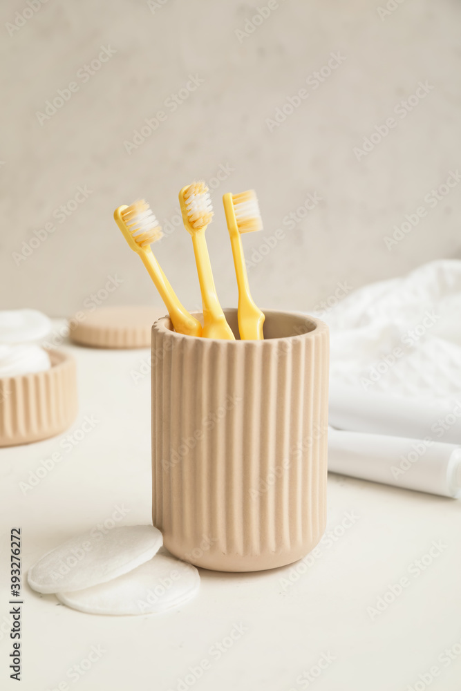 Holder with toothbrushes  on table in bathroom