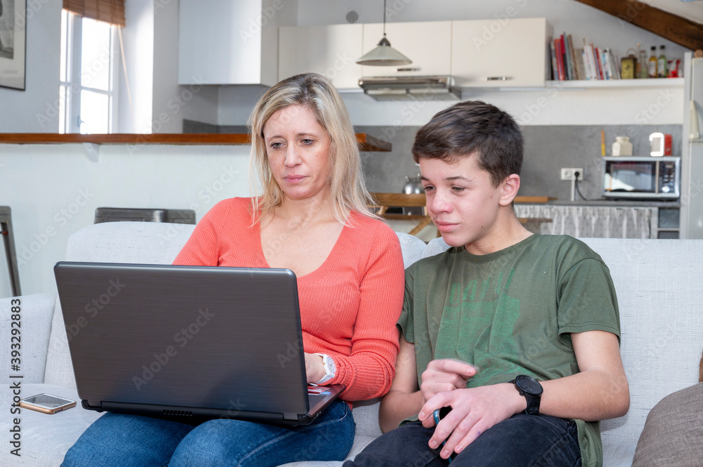 Adolescent et sa mère assis ensemble devant lécran dun ordinateur portable