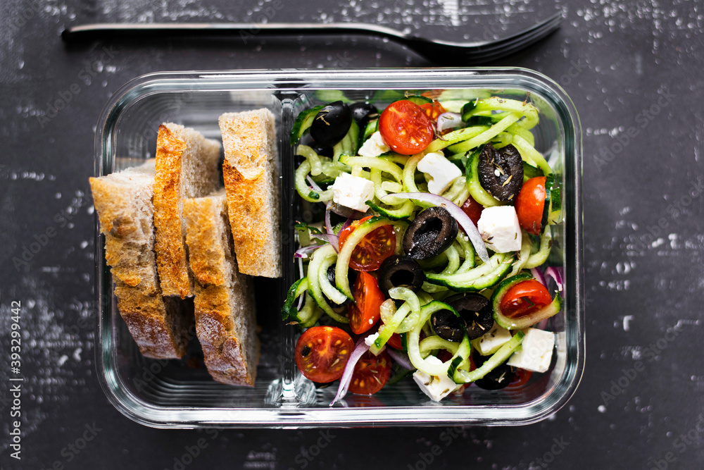 Greek salad with bread in a glass container