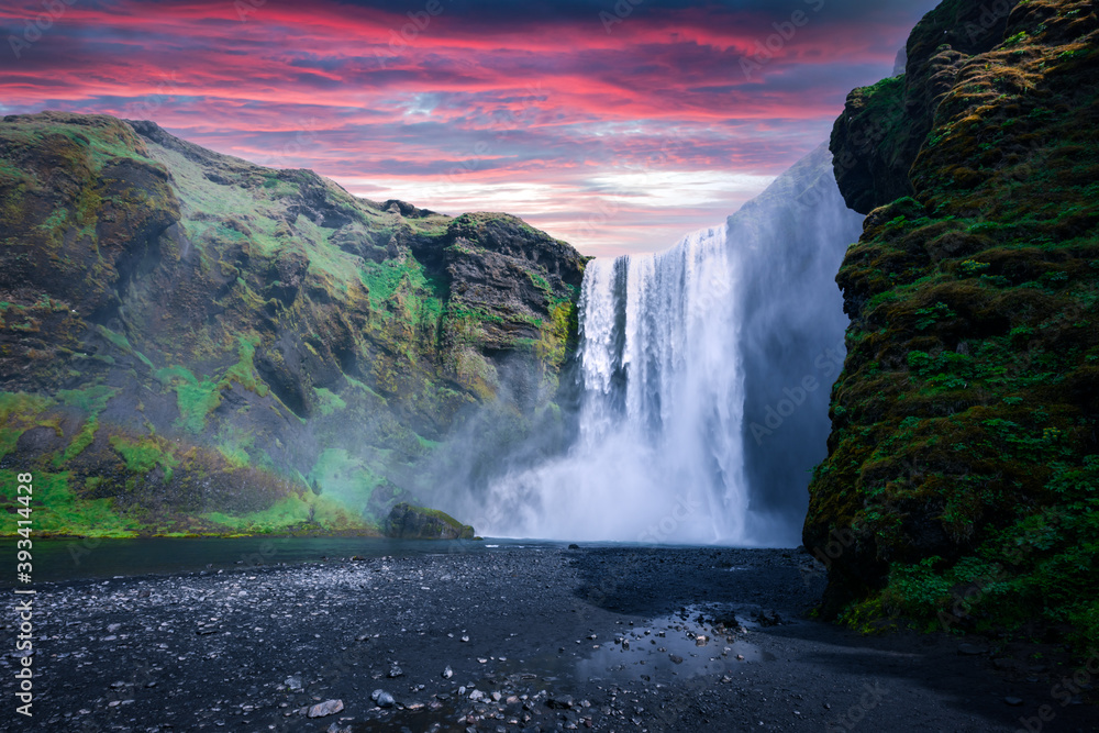 Famous Skogafoss waterfall on Skoga river in sunset time. Iceland, Europe. Great purple sky glowing 