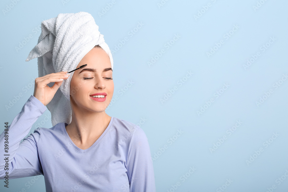 Young woman undergoing eyebrow correction procedure on color background