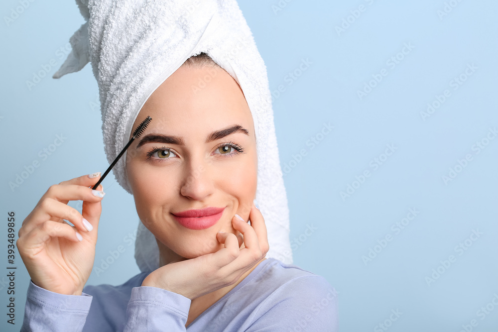 Young woman undergoing eyebrow correction procedure on color background