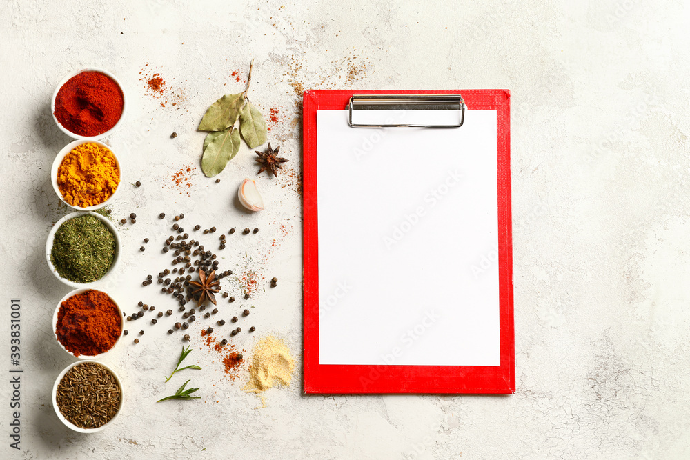 Spices and blank clipboard on white table