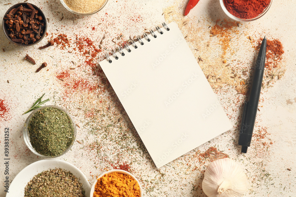 Spices and notebook for recipes on white background