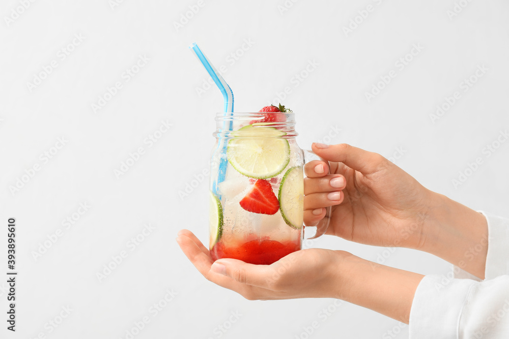 Woman holding jar of fresh strawberry lemonade on white background