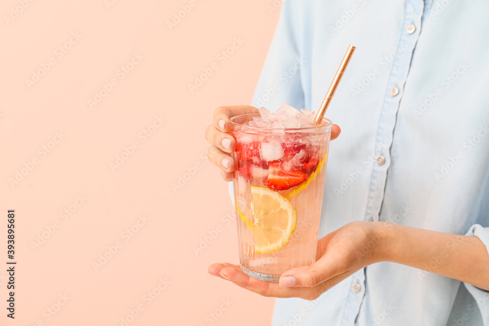 Woman holding glass of fresh strawberry lemonade on color background