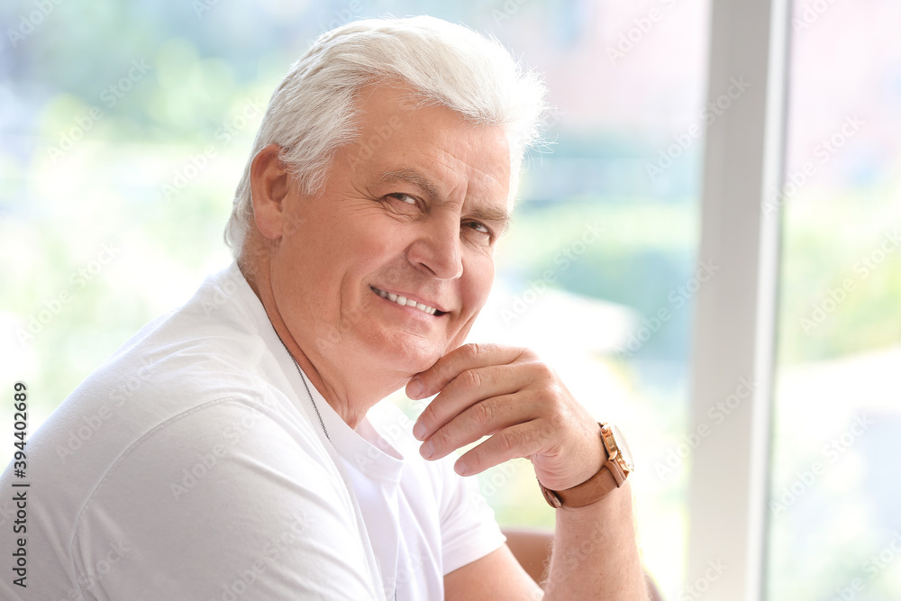 Portrait of senior man near window at home