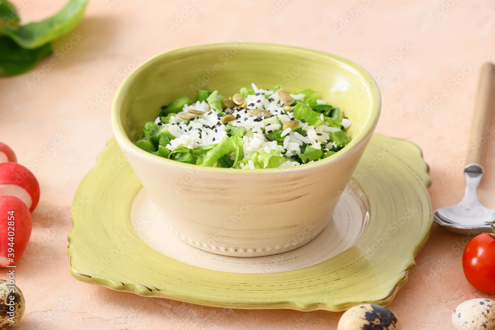 Bowl of delicious rice salad with vegetables on light background