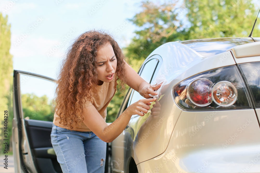 African-American woman cleaning her car outdoors