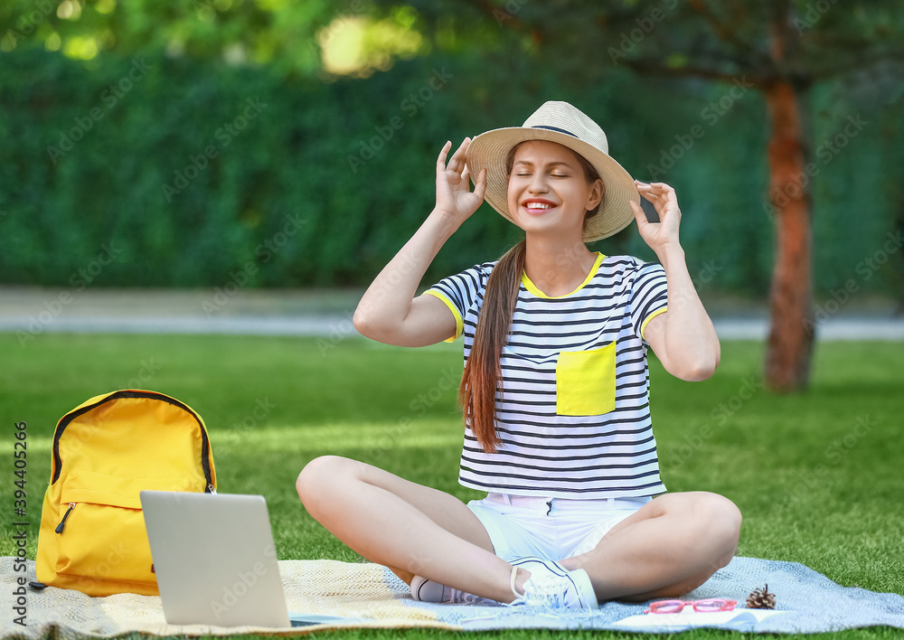 Beautiful female student with laptop in park