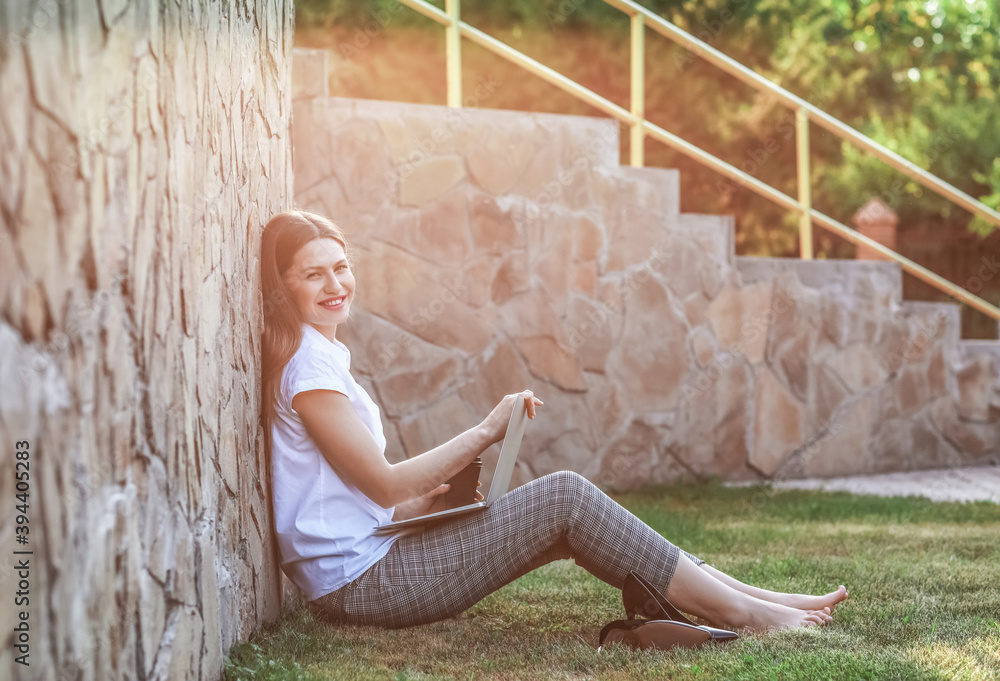 Beautiful young businesswoman with laptop in park