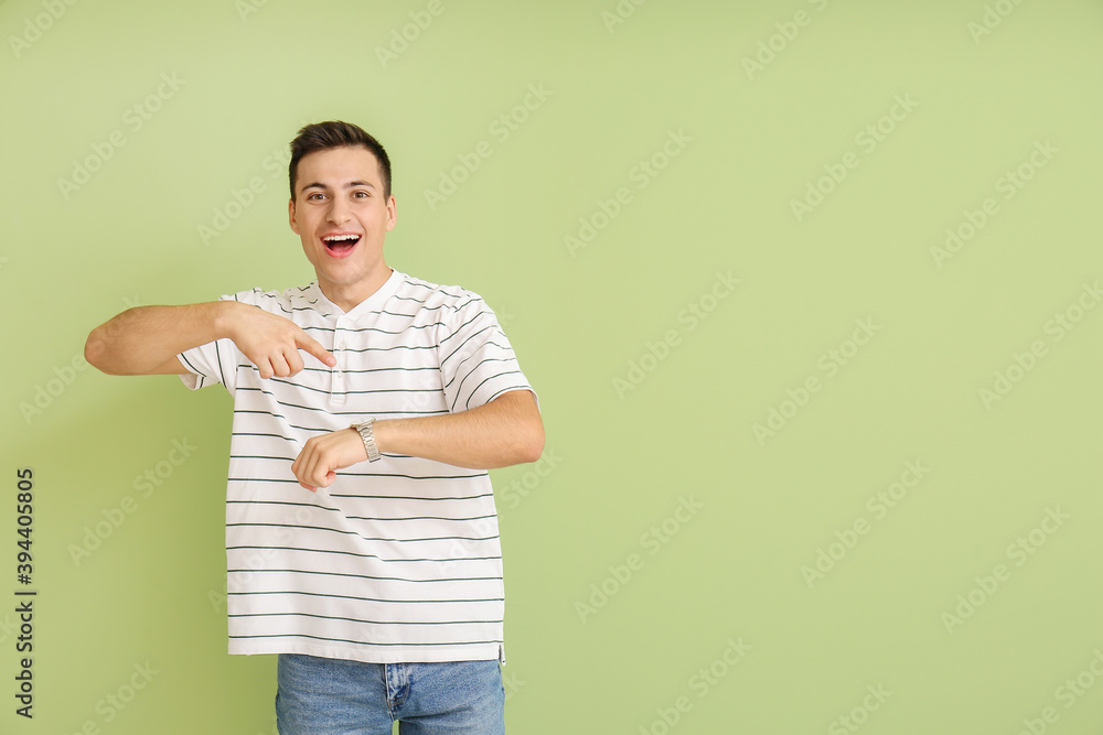 Happy man with wristwatch on color background