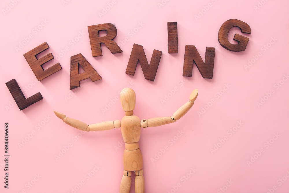 Wooden mannequin with word LEARNING on color background