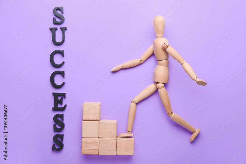 Wooden mannequin with word SUCCESS and cubes on color background