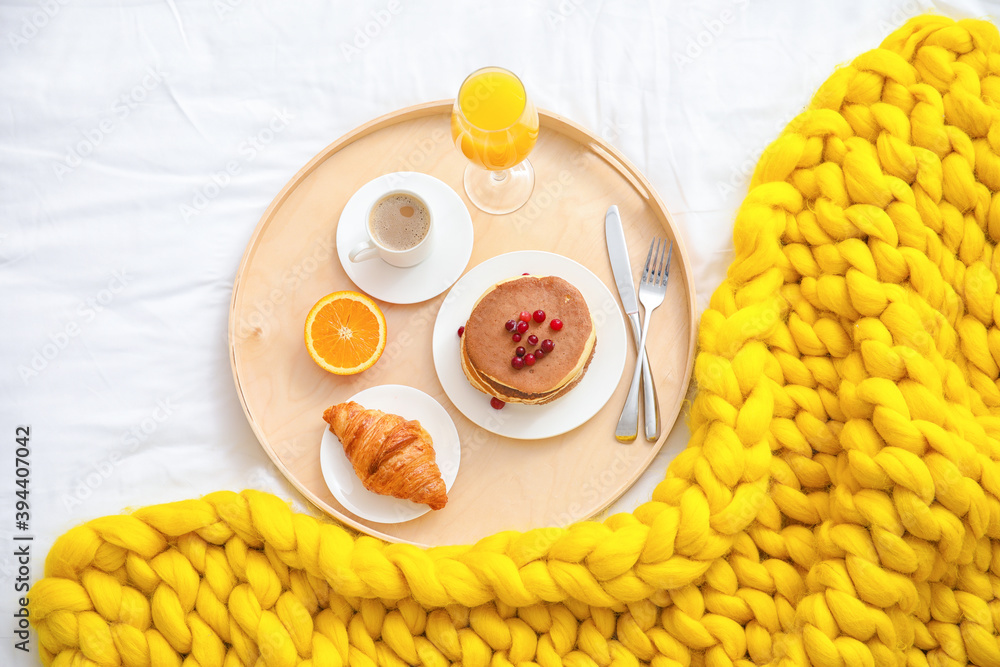 Tray with tasty breakfast on bed, top view