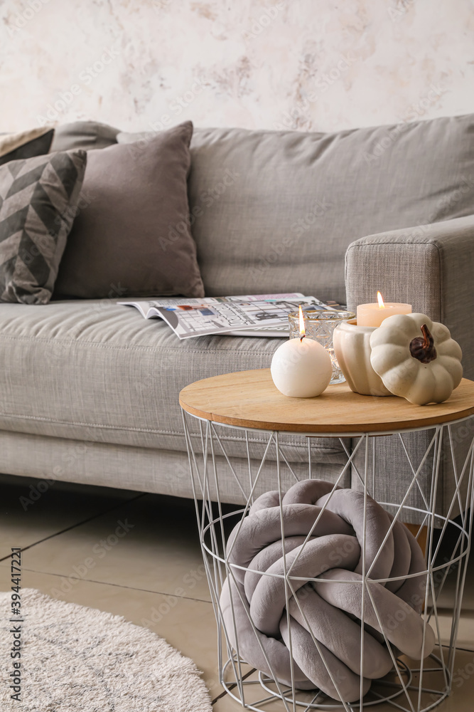 Table with burning candles and sofa in interior of room