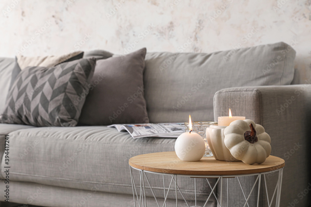 Table with burning candles and sofa in interior of room