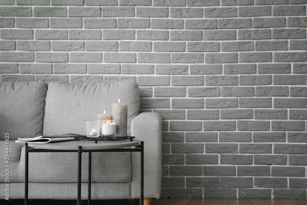 Stylish interior of living room with sofa, table and burning candles