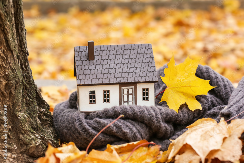 Figure of house and scarf in autumn park. Concept of heating season