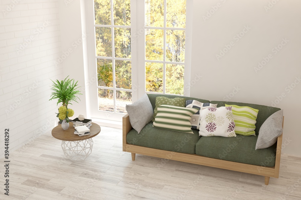 Stylish room in white color with sofa and autumn landscape in window. Scandinavian interior design. 