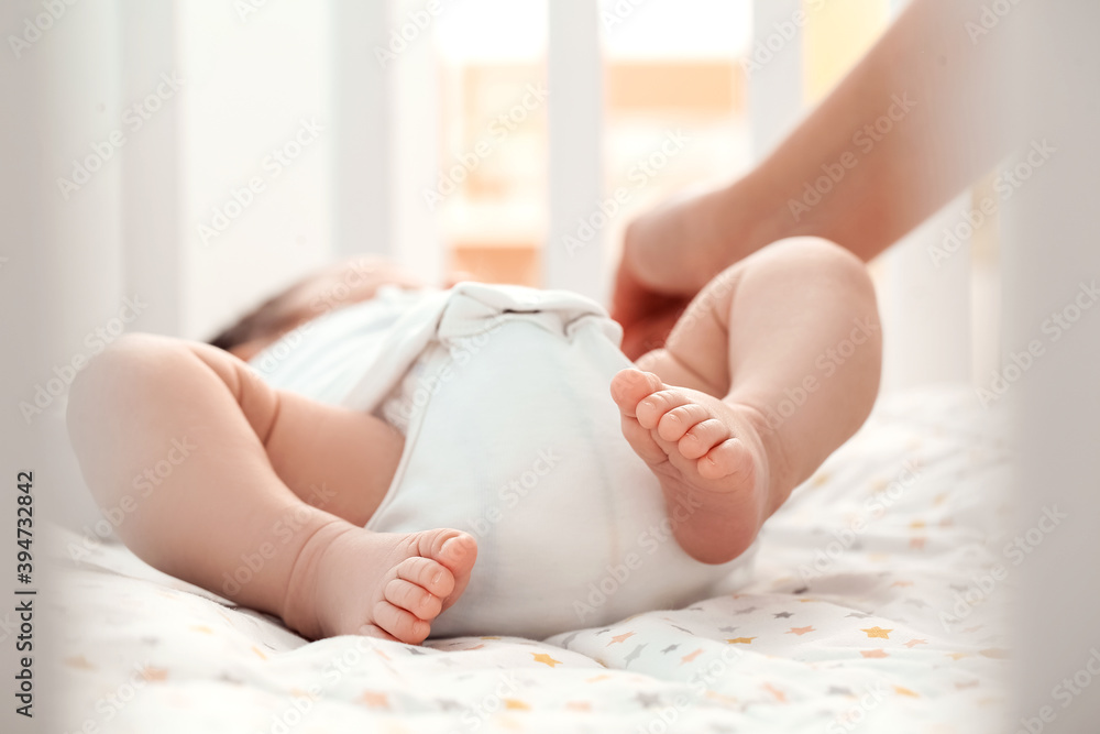 Mother with cute little baby lying in crib