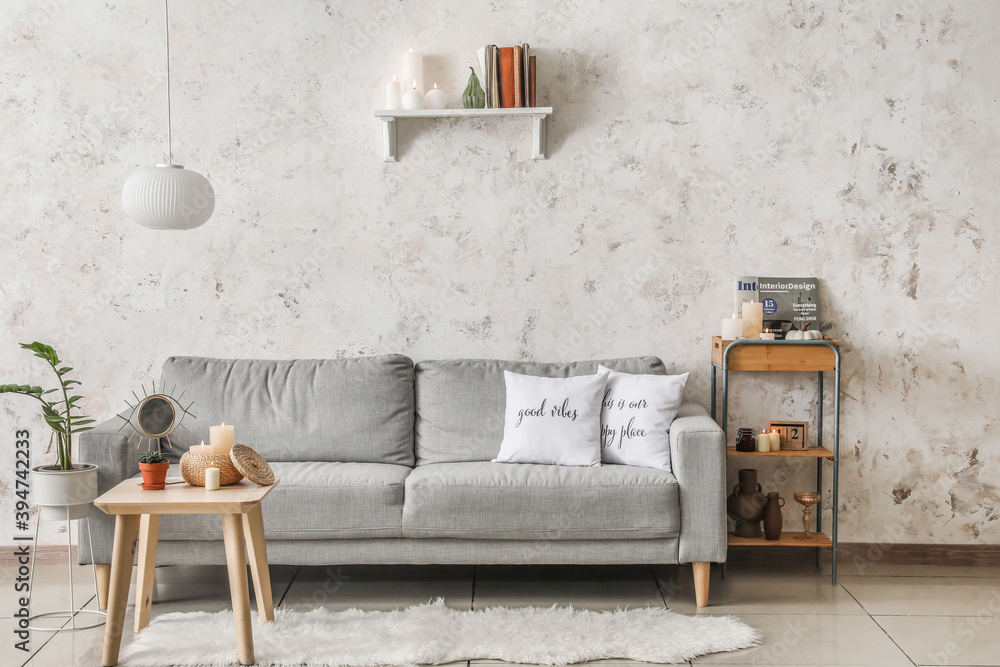 Stylish interior of living room with grey sofa and burning candles