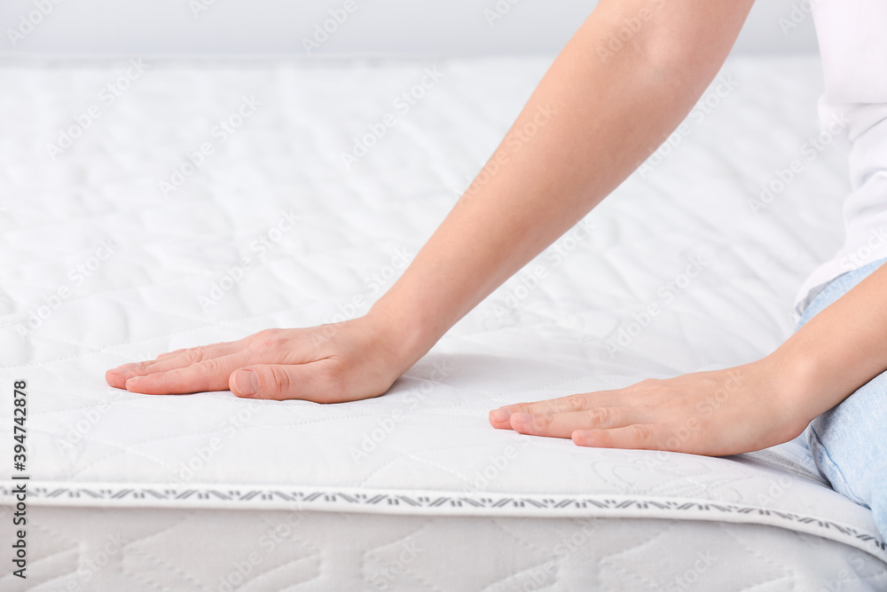 Woman sitting on soft orthopedic mattress, closeup