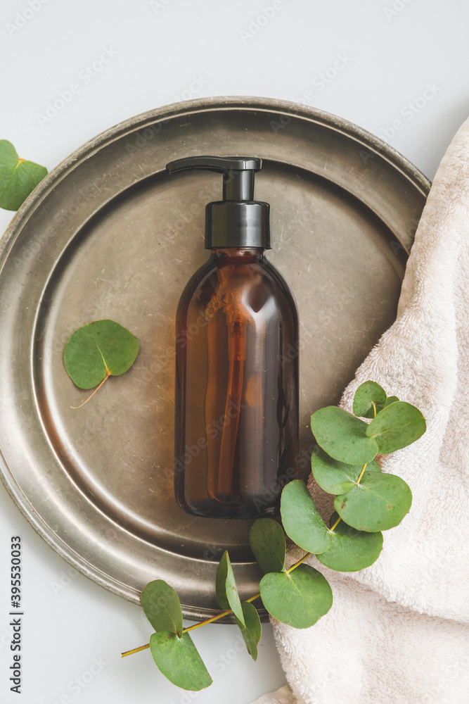 Dispenser bottle with natural eucalyptus cosmetics on light background