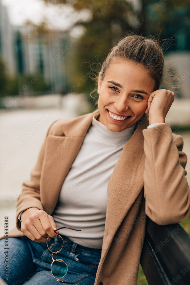 Sitting alone at city center, smiling.