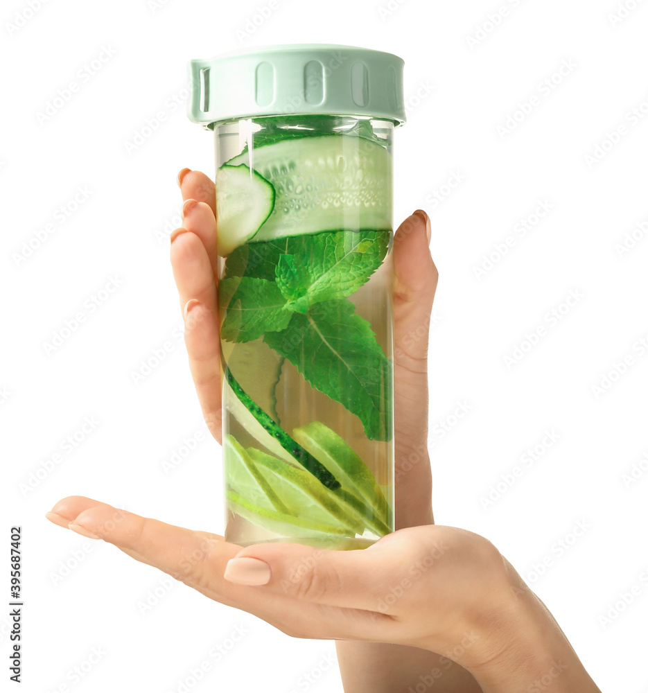 Hand with bottle of clean water with cucumber and lime on white background