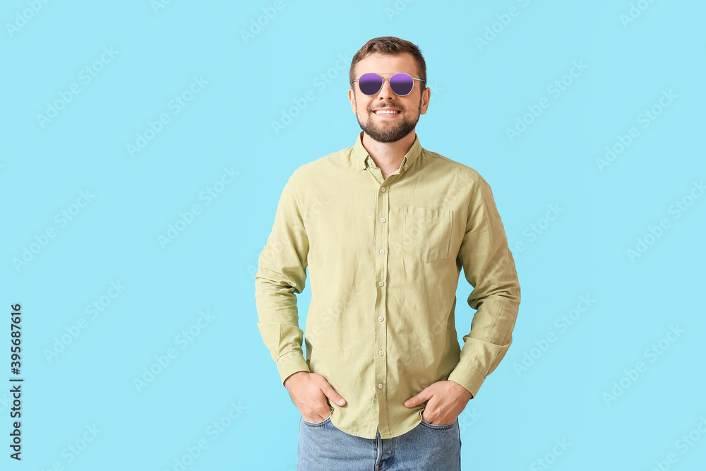 Handsome man with stylish sunglasses on color background