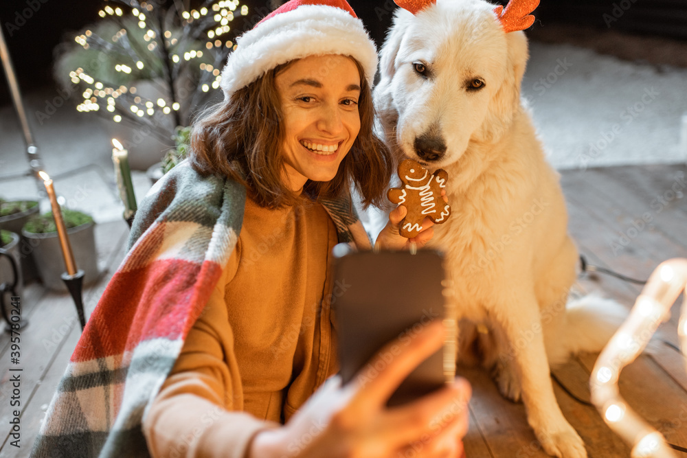 Portrait of a woman in christmas hat and plaid with her cute dog celebrating a New Year holidays at 