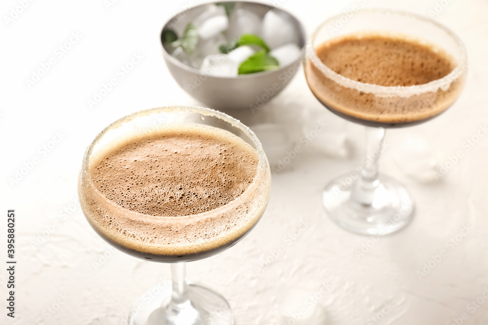 Two glasses of tasty espresso martini cocktail on light background