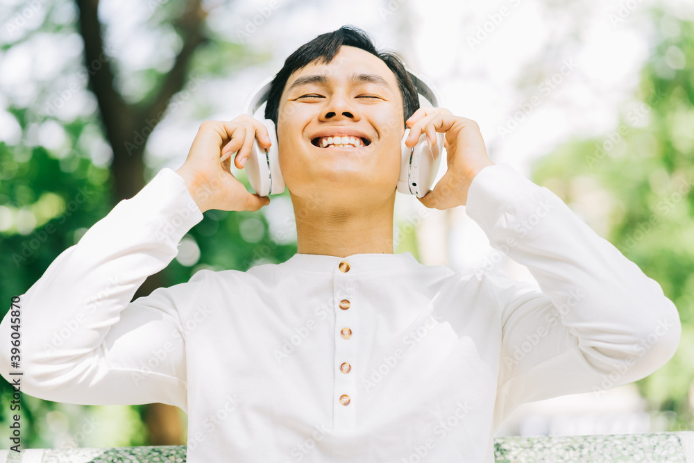 Handsome Asian man enjoying music at the park