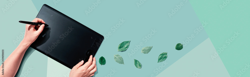 Graphic pen tablet with green leaves - flat lay