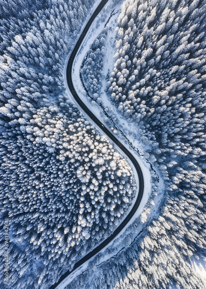 Winter chill. Natural winter landscape from air. Aerial view on the road and forest at the winter ti