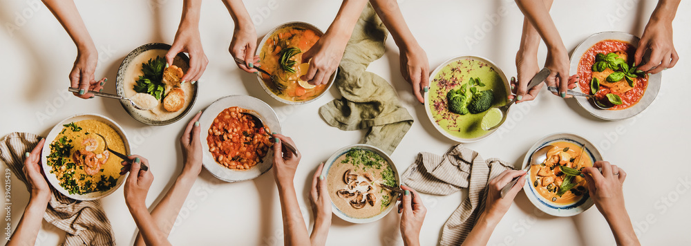 人们在吃秋冬奶油素食汤。人们用汤盘和b平放双手