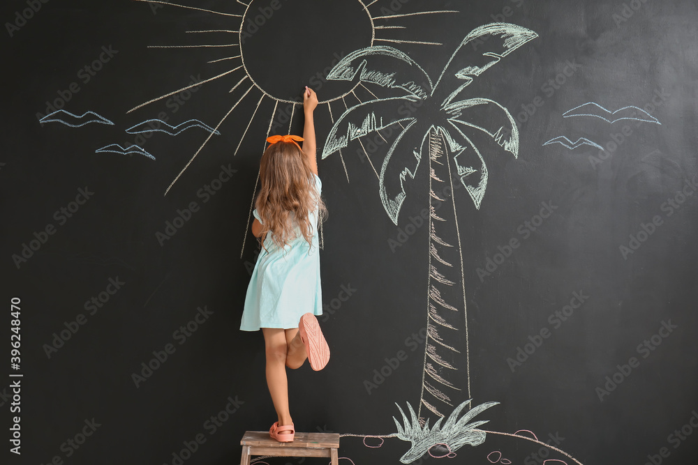 Cute little girl drawing sun on black wall