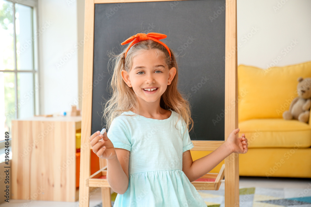 幼儿园里拿粉笔的可爱小女孩