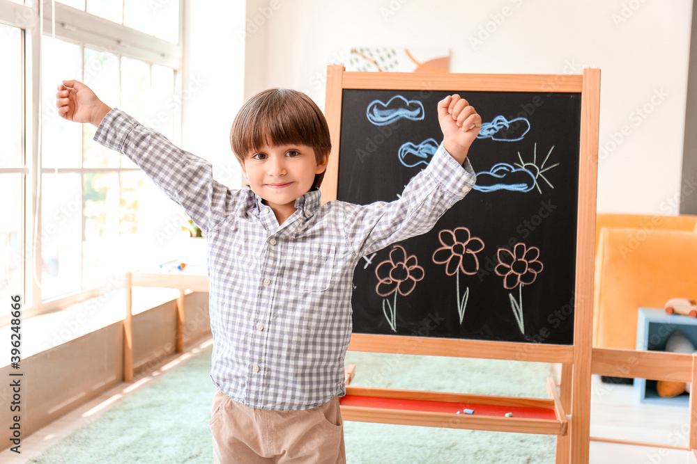 幼儿园黑板上画着花的可爱小男孩