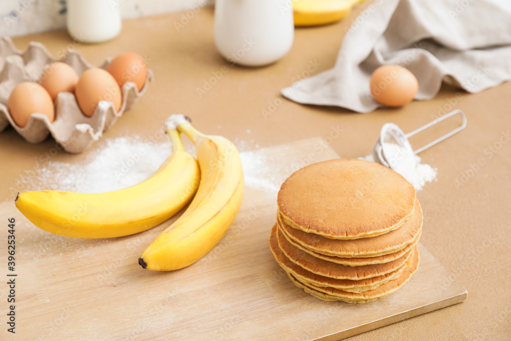 Board with tasty banana pancakes on table