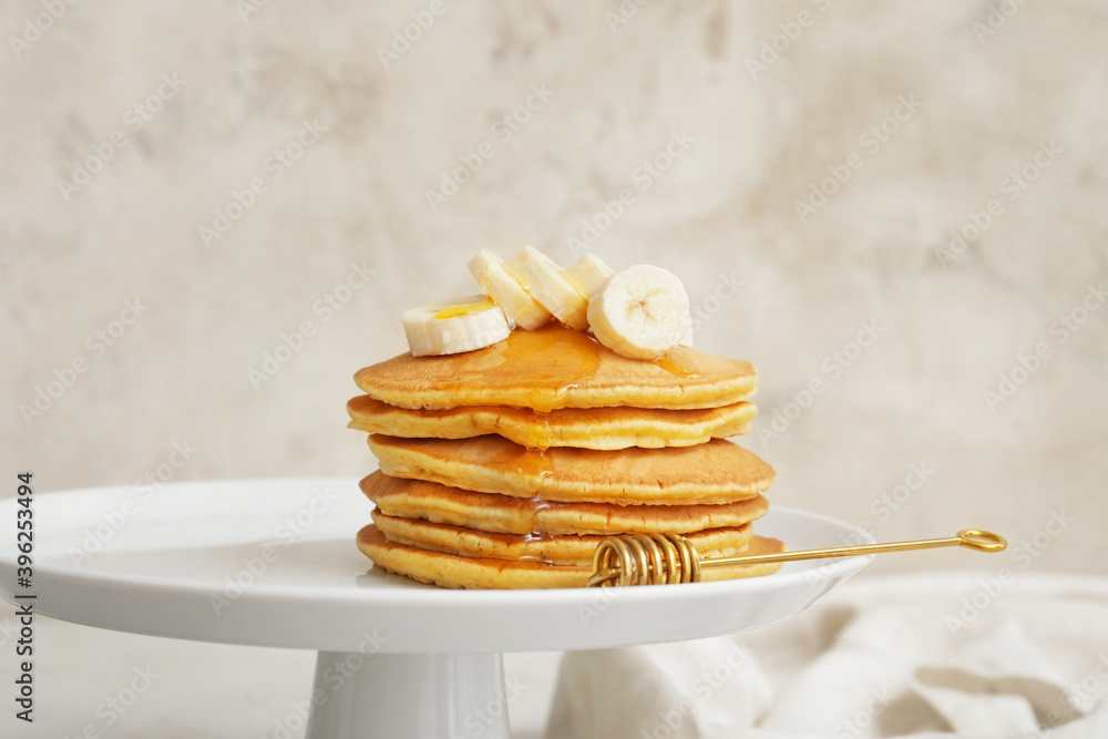 Dessert stand with tasty banana pancakes on grey background