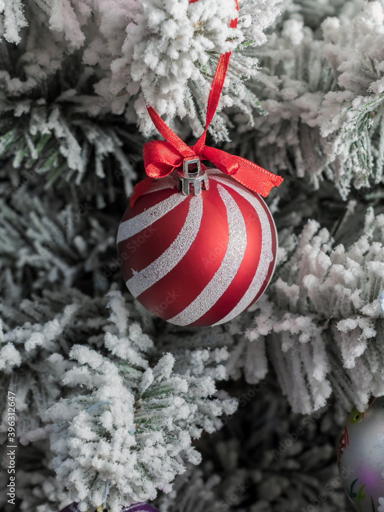 A christmas decorations are on the Christmas tree. The red ball on an artificial Christmas tree.