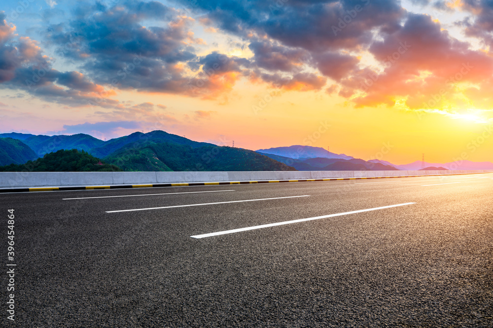 Asphalt highway and green mountain natural landscape at sunset.