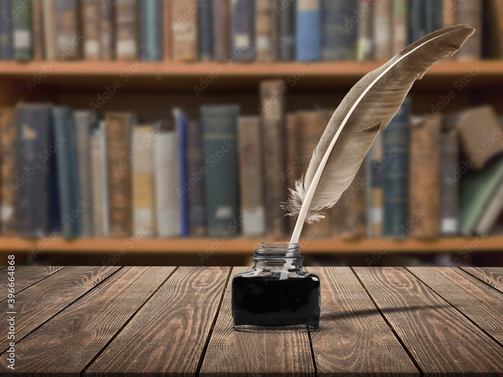 Feather quill pen and glass inkwell on desk