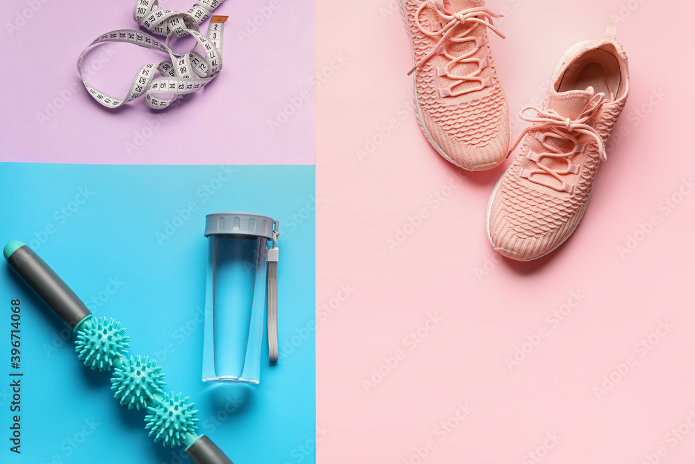 Sports equipment with bottle of water and measuring tape on color background