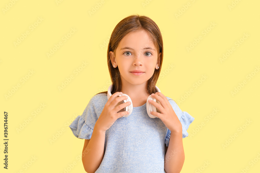 Cute little girl with headphones on color background