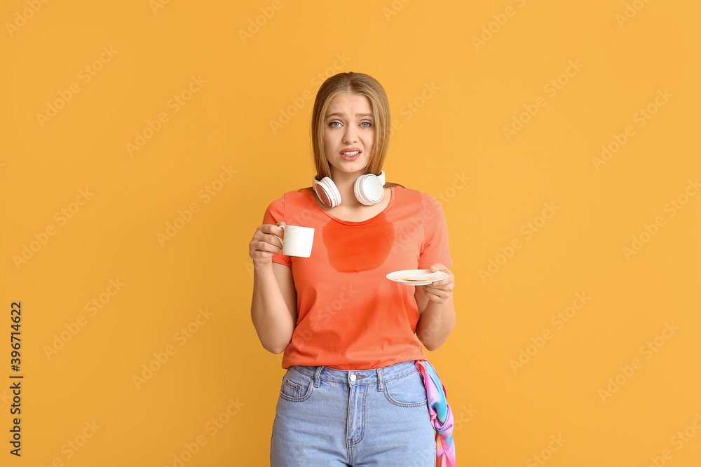 Troubled young woman with coffee stains on her t-shirt on color background